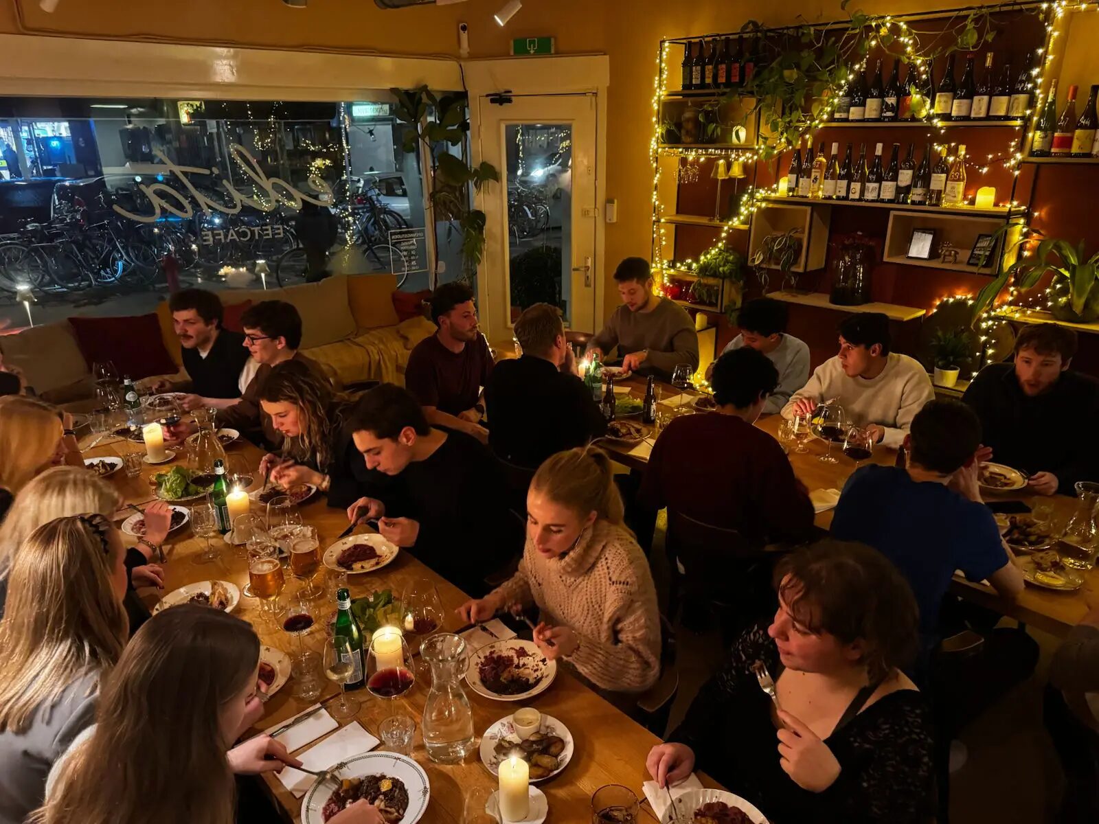 Een groep aan lange tafels bij Edita, met lichtjes en kaarsen